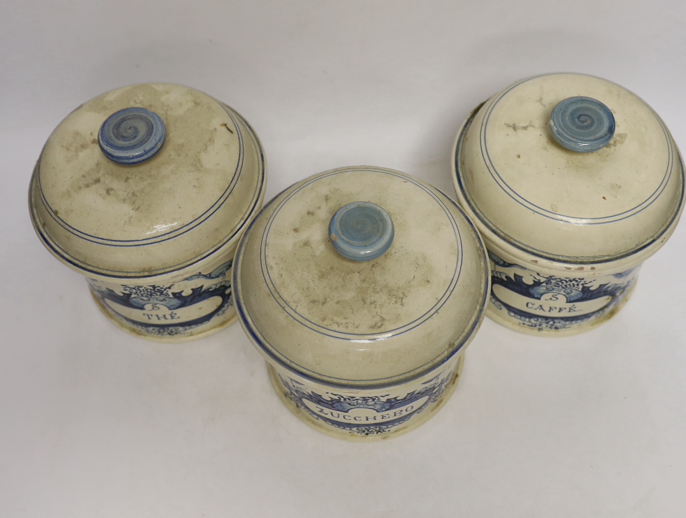 Three French cream and blue glazed storage jars and covers, Caffé, Thé and Zucchero, 18cm high